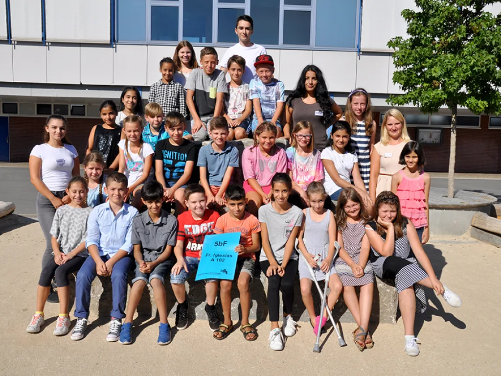 Klassenfoto einer neuen fünften Klasse mit blauem Klassenschild.